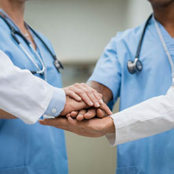 Two doctors holding hands in a circle